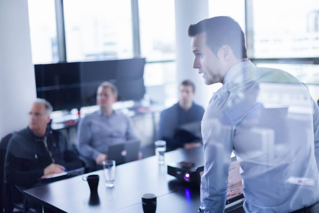 Training professional presenting data to team in a boardroom.